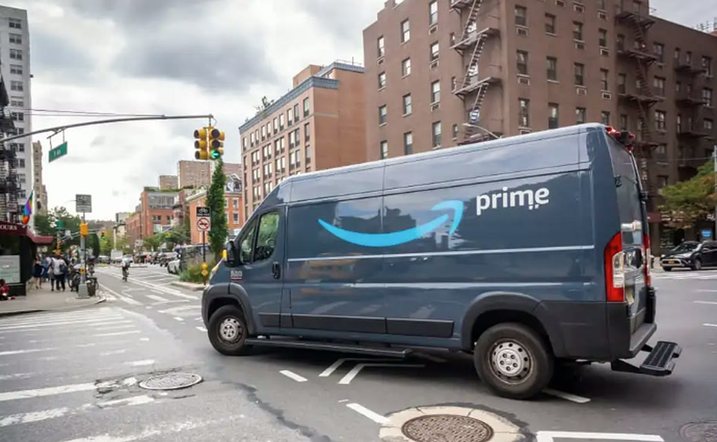 An Amazon Prime cargo delivery van turning through a city intersection